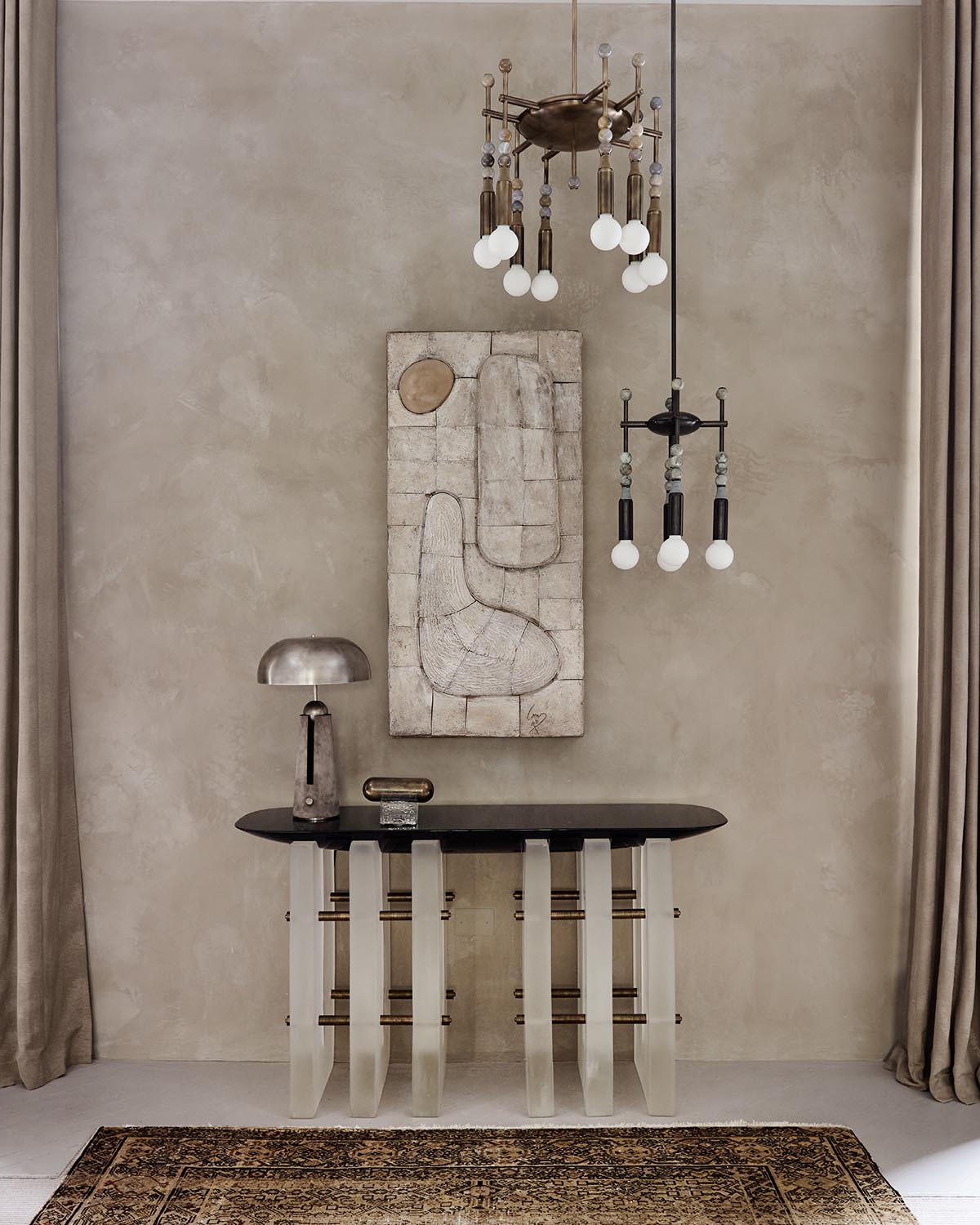 Minimalist interior with a sculptural console table, abstract wall art, two pendant lights, and a modern metallic table lamp