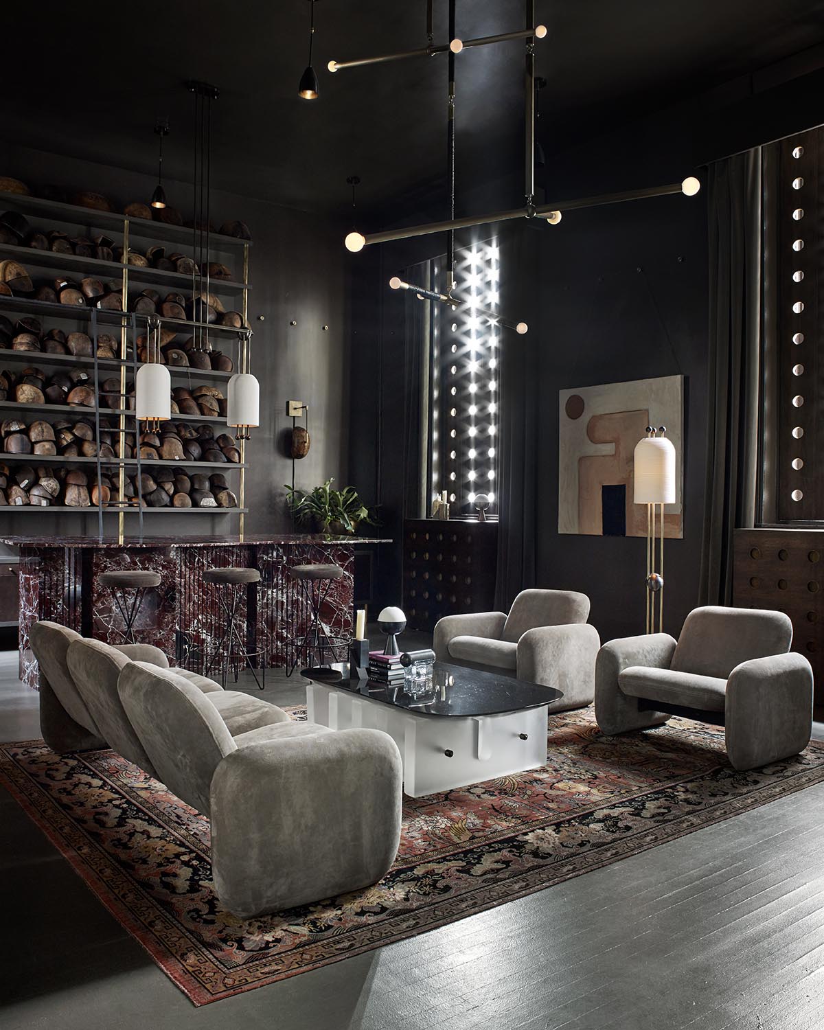 Modern living room with plush gray armchairs and sofa around a black and white coffee table on a patterned rug