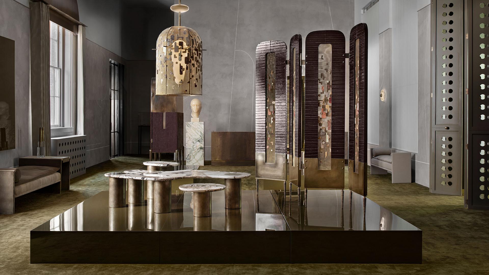 Spacious room with modern sculptural furniture and art pieces on olive green carpet beneath soft natural light from tall windows