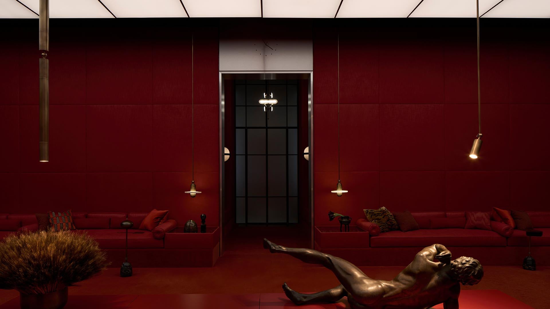 Minimalist interior with deep red upholstered seating, warm pendant lights, and a reclining bronze sculpture on the floor