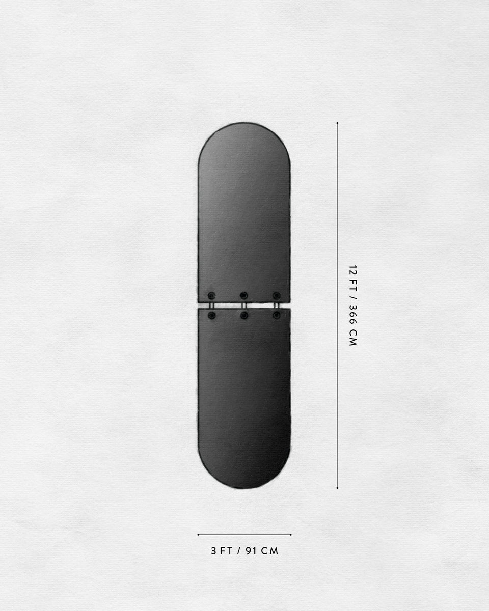 Black elongated oval-shaped object with a hinge in the center on a white textured background with measurement markings