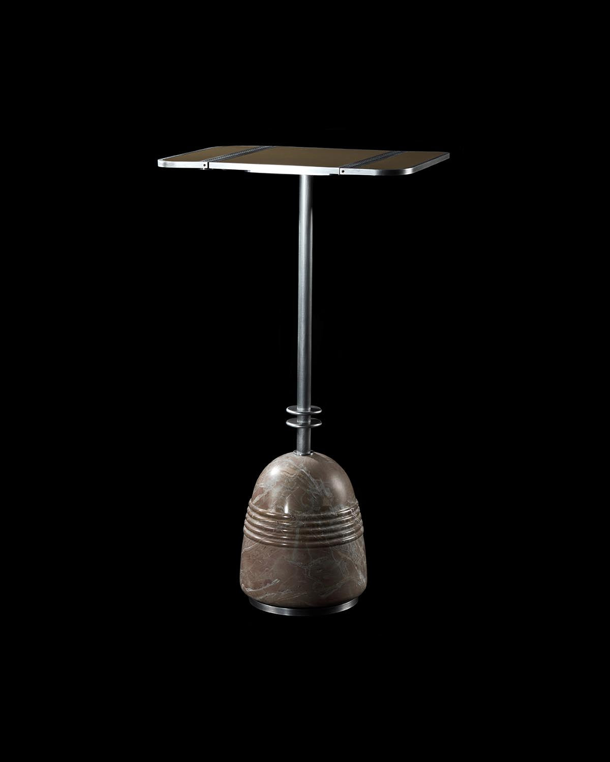 Square cocktail table with slim metal stem and rounded textured stone base against black background