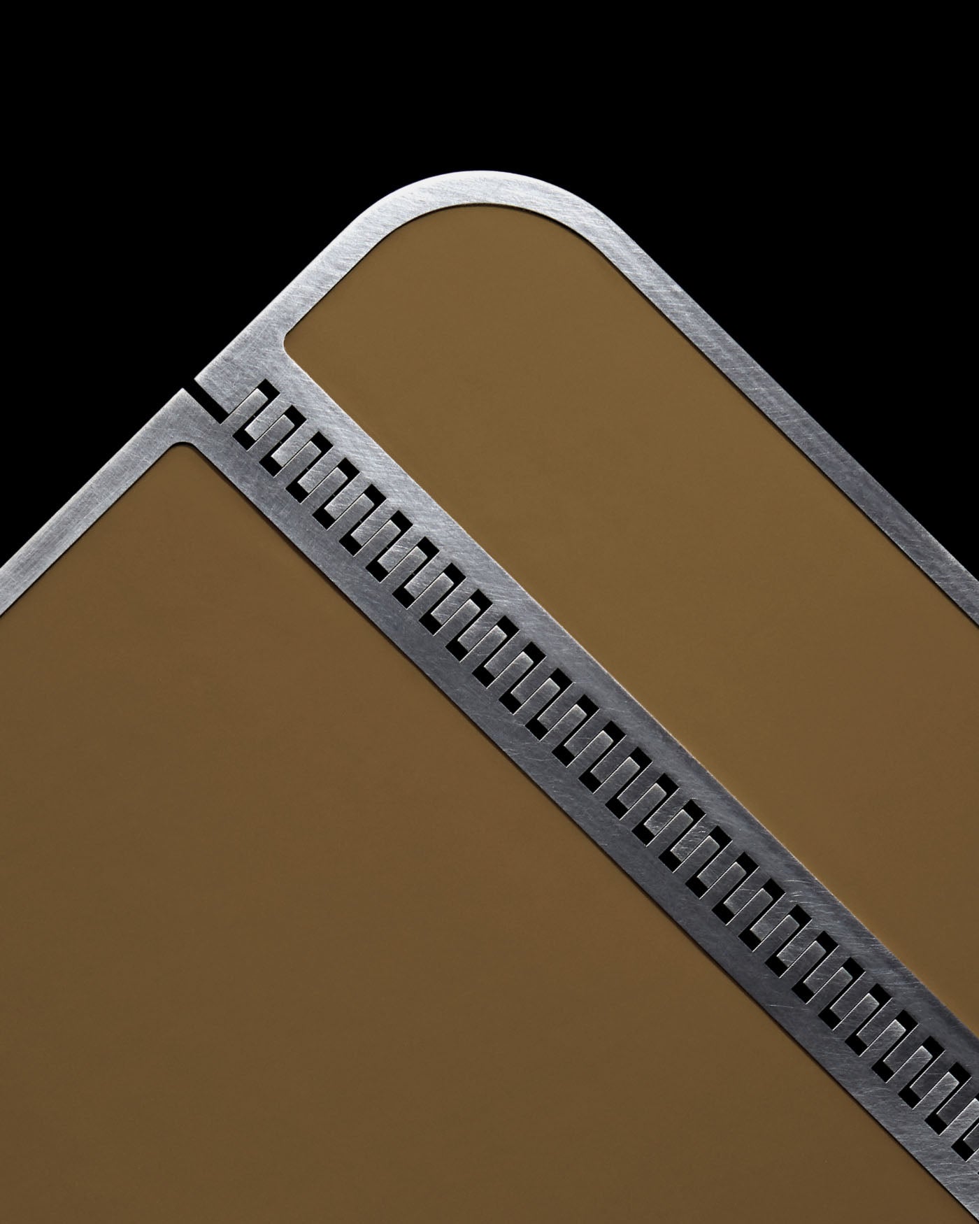 Close-up of a brown cocktail table corner with brushed steel edge and rectangular cut-out details against black background