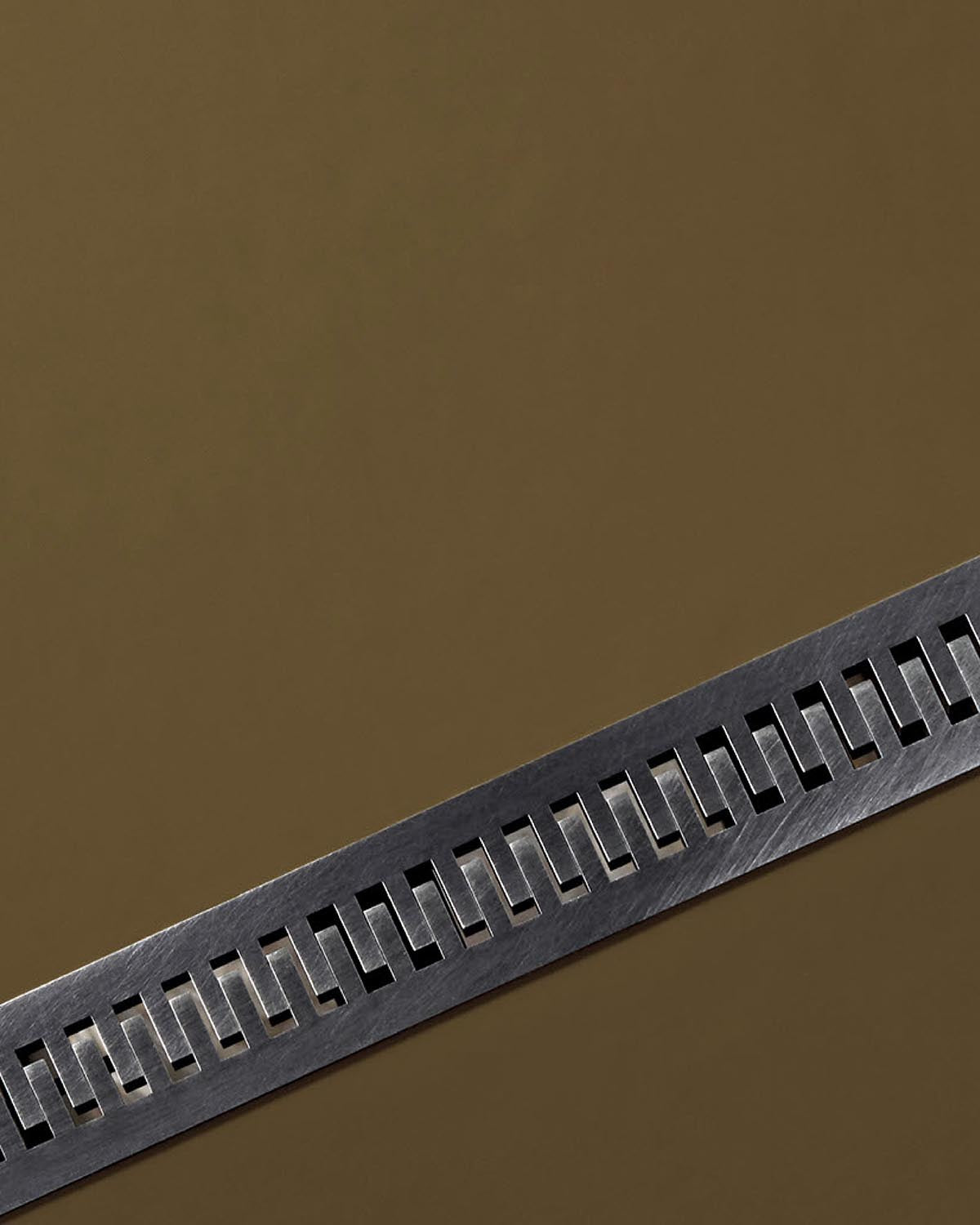 Close-up of brushed metal strip with rectangular cutouts set against a muted brown background