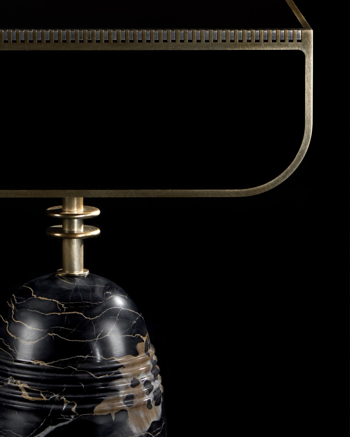 Close-up of a black marble base with gold veining and brass metal frame detail on a side table against black background