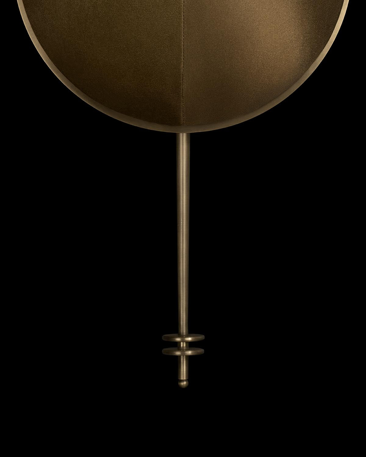 Minimalist bronze wall light with deep circular shade and thin cylindrical arm against black background
