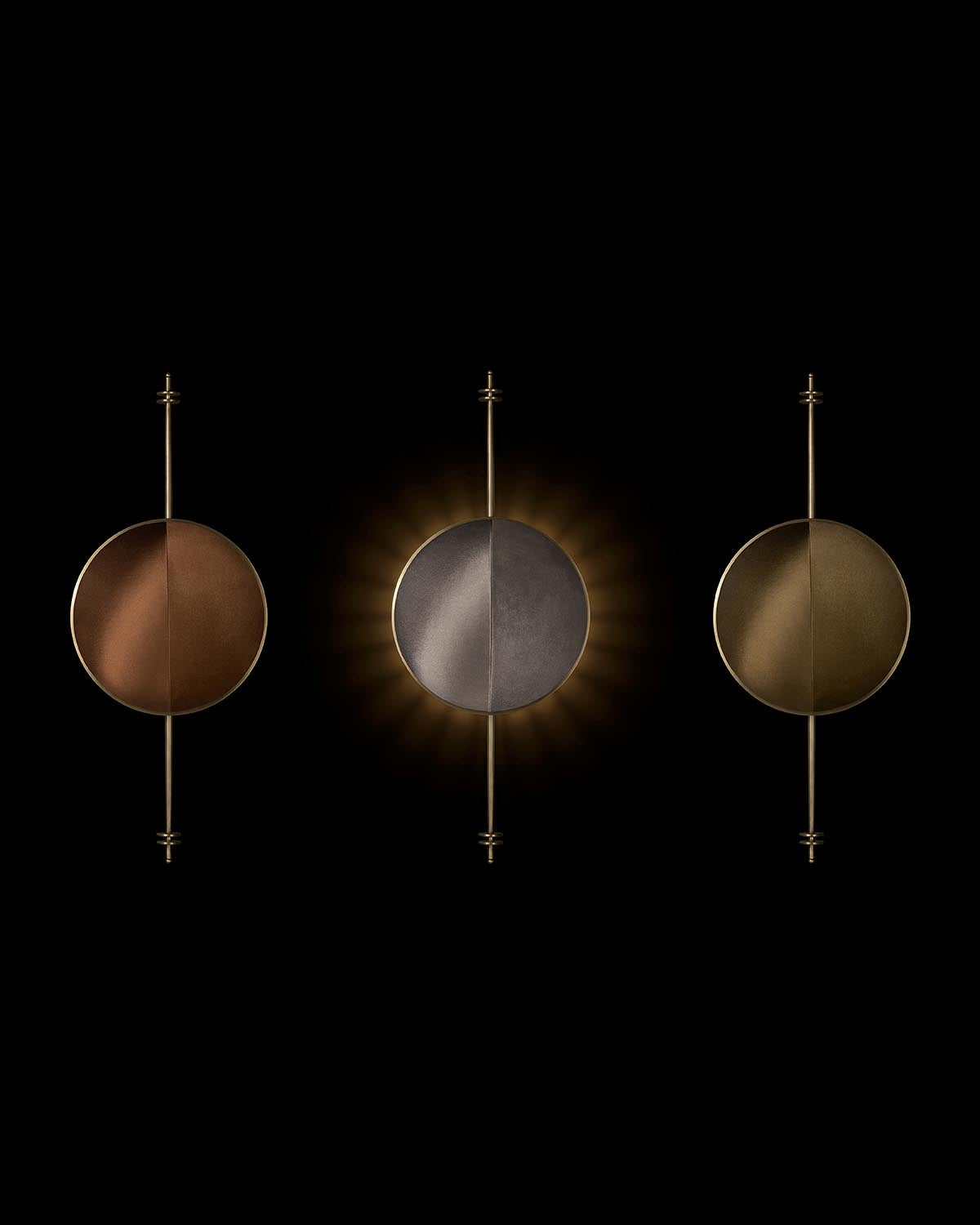 Three round metal wall sconces with vertical rods, featuring copper, dark gray, and brass finishes on a black background