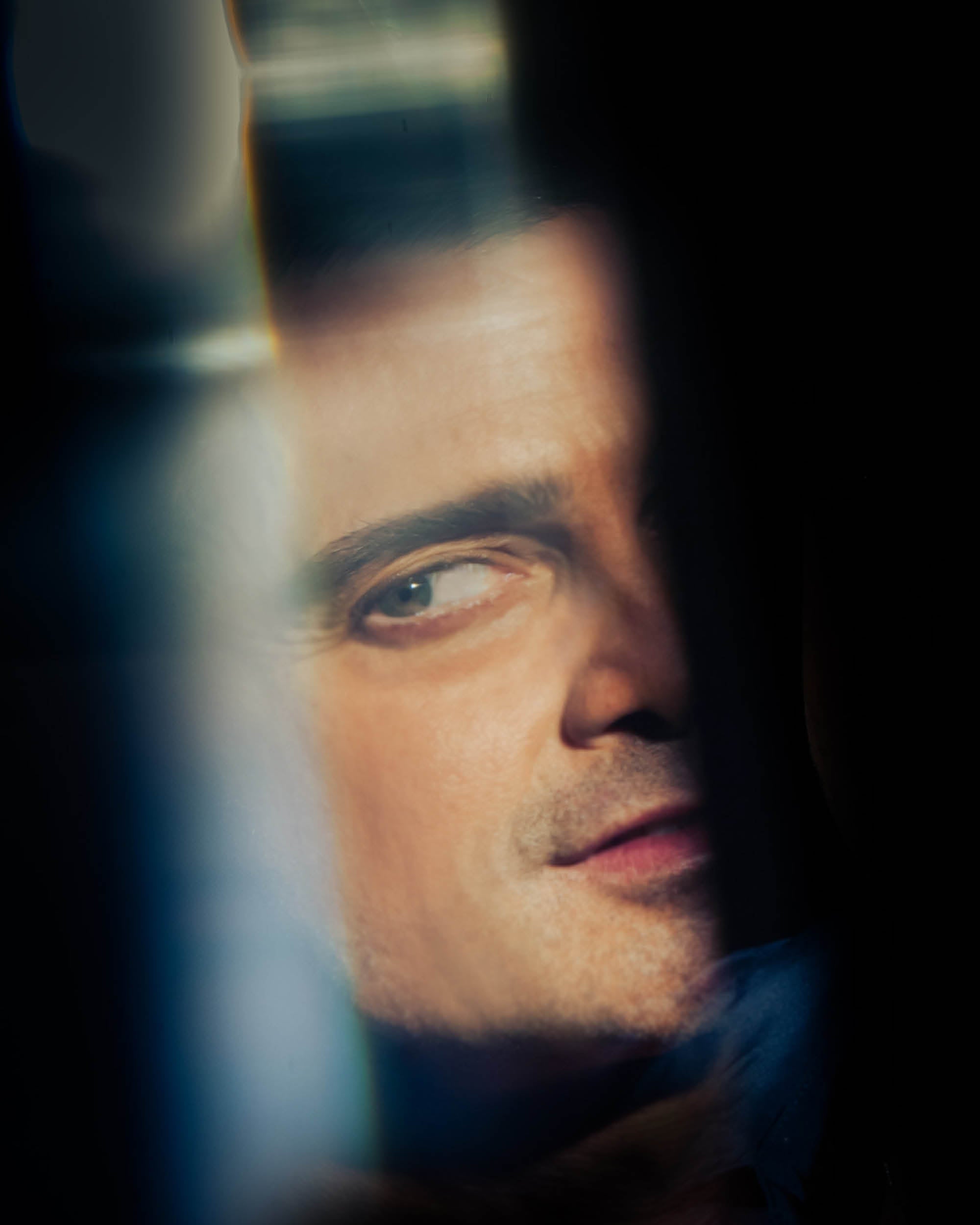 Close-up of a man's face partially obscured by shadow with soft focus and warm lighting effects