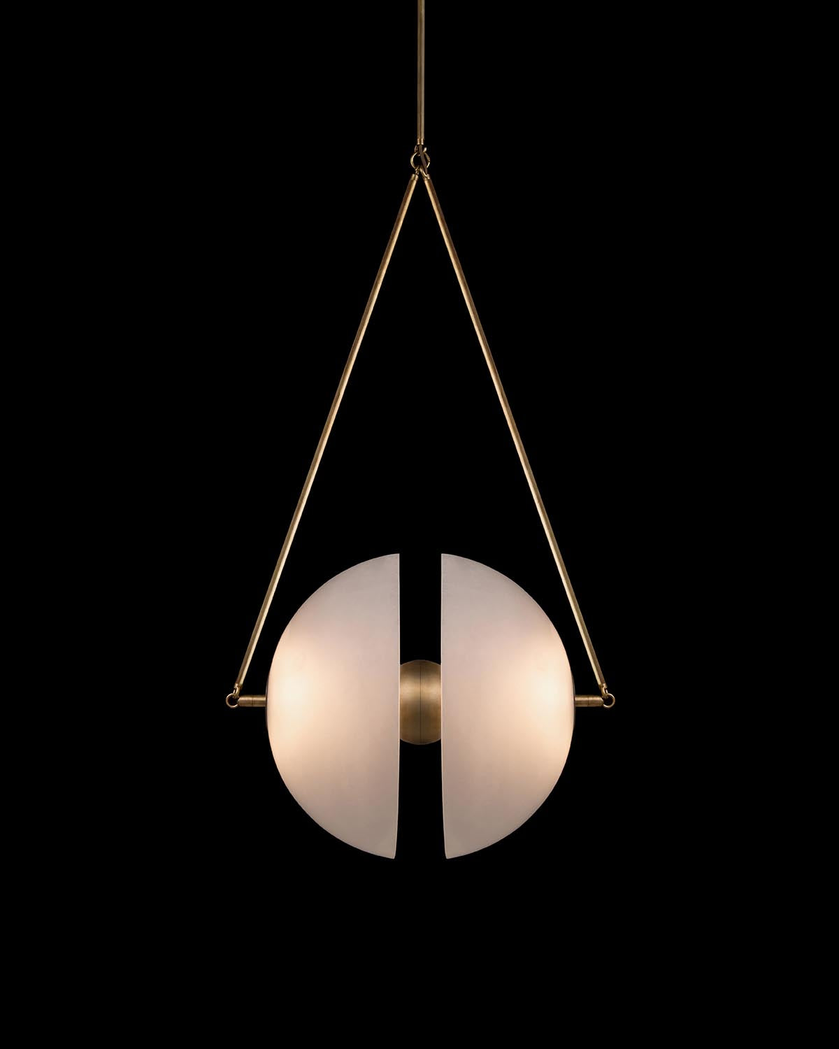 Minimalist pendant light with two frosted glass semicircles separated by a brass centerpiece hanging from brass rods