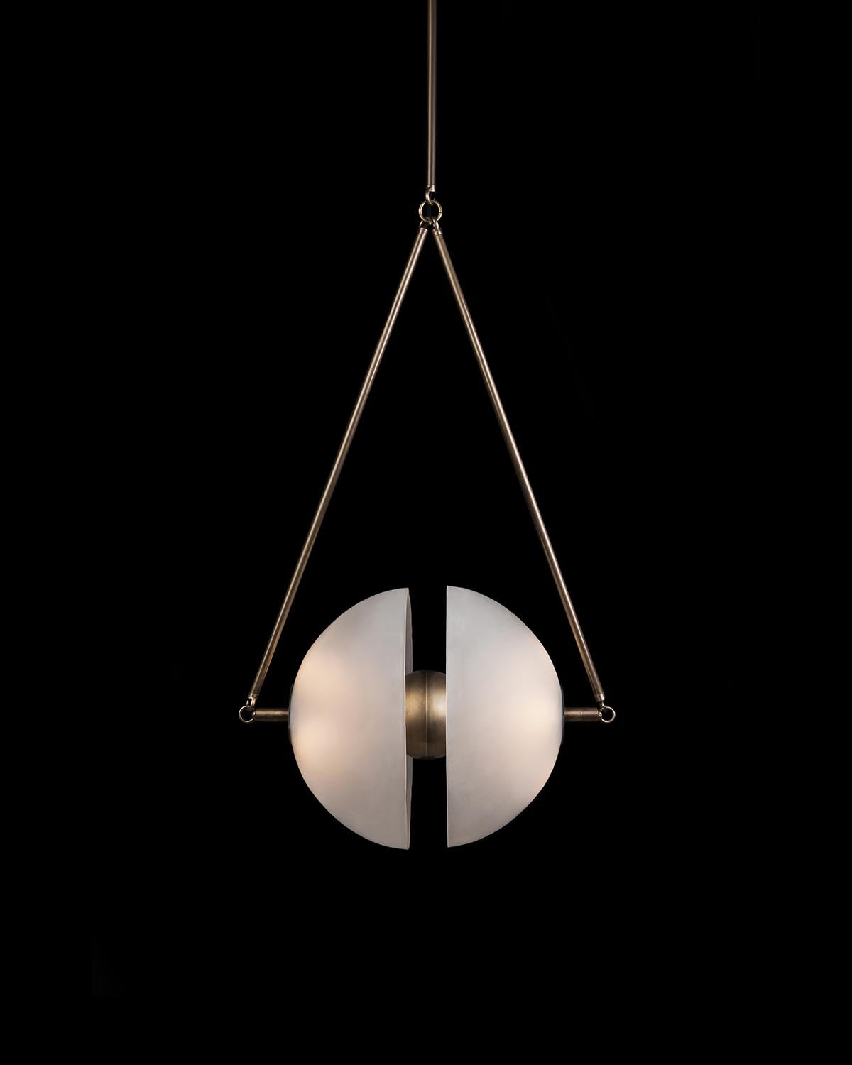 Modern pendant light with two frosted glass hemispheres separated by a brushed metal center, suspended by a triangular brass frame