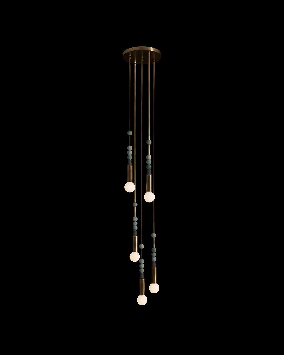 Vertical pendant light installation with five illuminated bulbs and spherical gray accents on black background