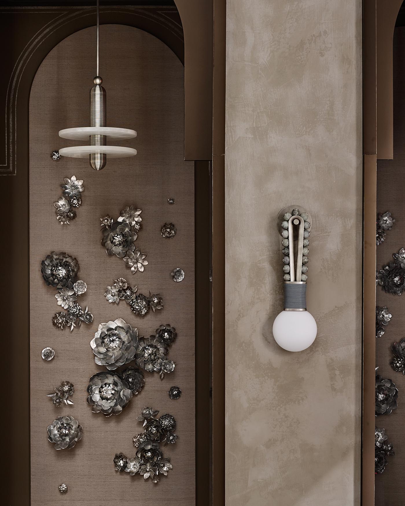 Minimalist loop sconce with a round bulb and decorative beaded strap mounted on a textured beige wall panel