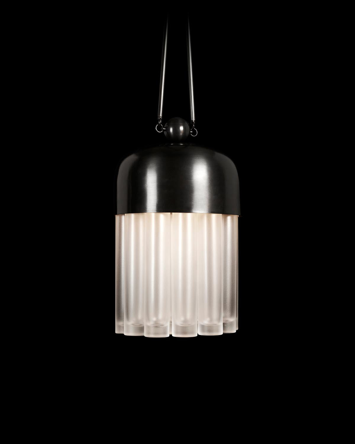 Pendant light with dark metal dome and frosted glass cylindrical tubes hanging against a black background