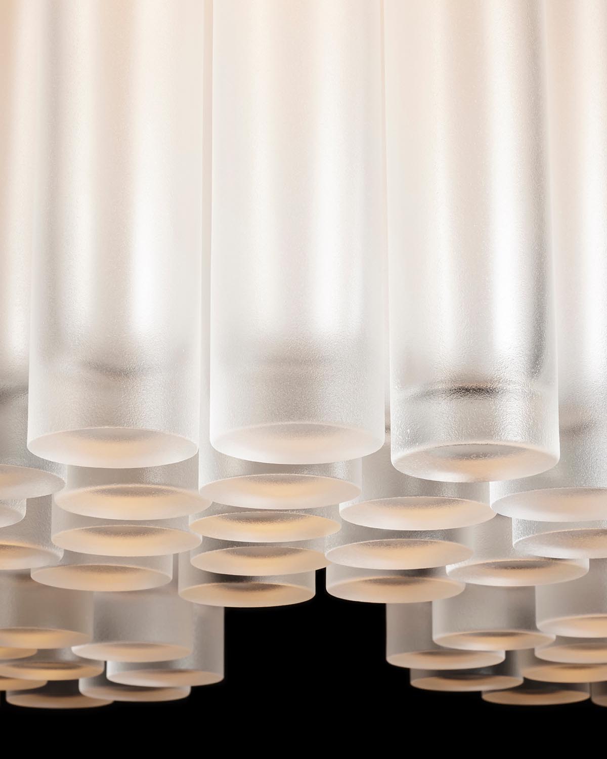 Close-up view of frosted cylindrical glass tubes arranged in a clustered pattern against a black background