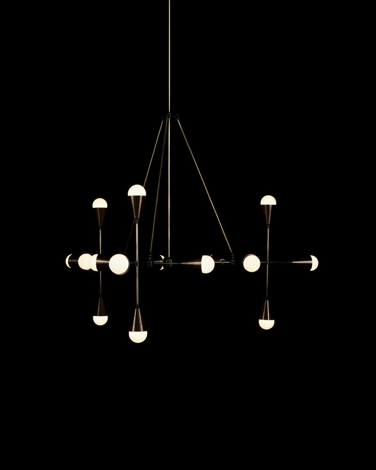 Modern TRIAD pendant light with multiple glowing white bulbs on dark metal arms against black background