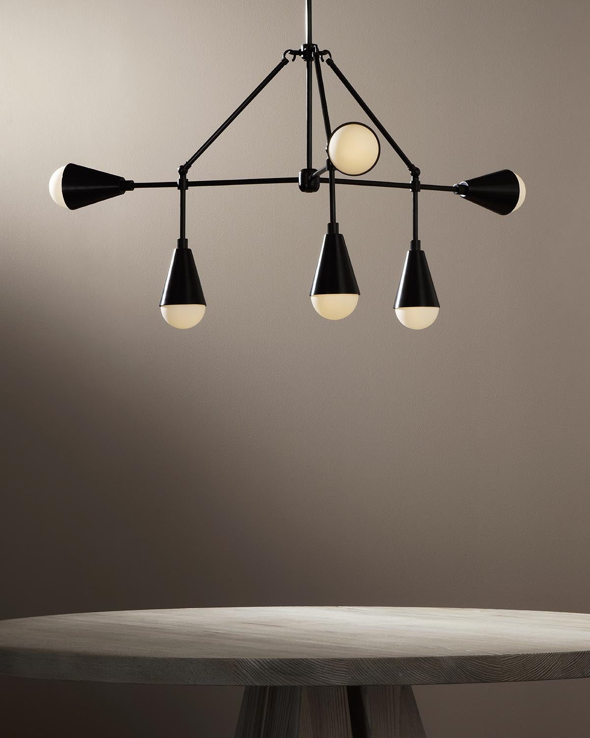 Modern black metal pendant light with six conical shades and round diffusers above a wooden table