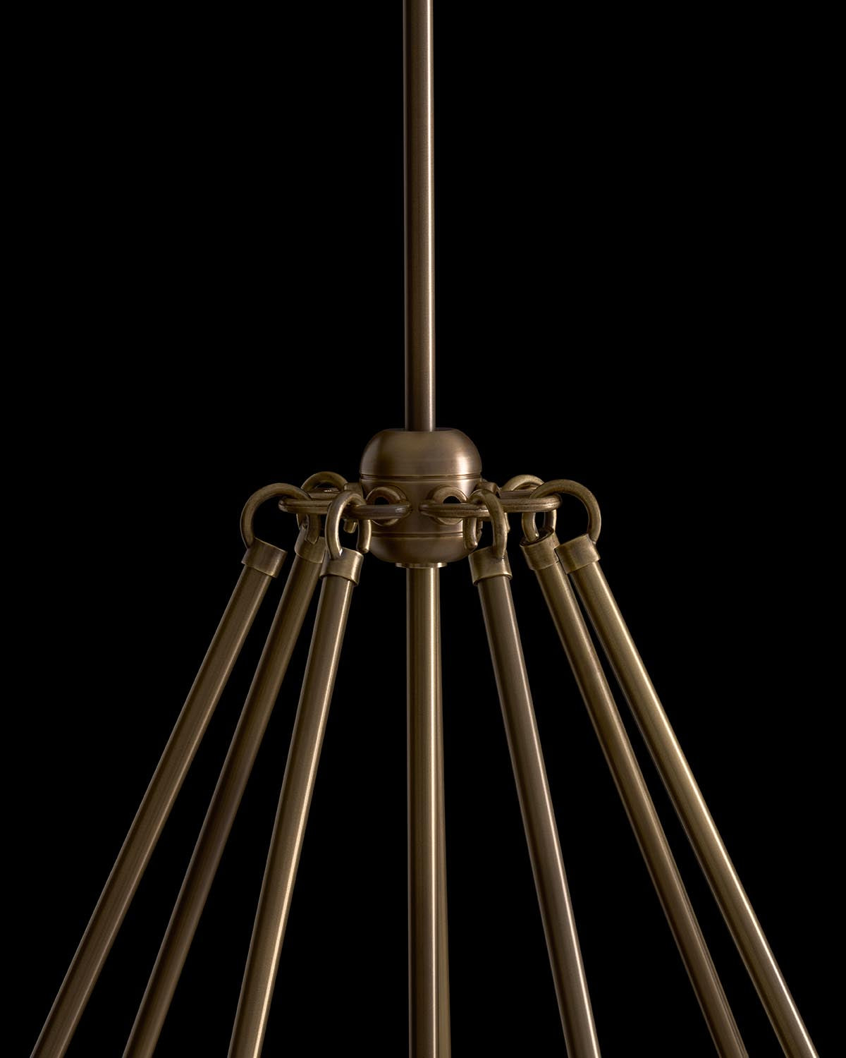 Close-up of bronze triangular pendant light fixture with seven rods extending from a central spherical hub on black background