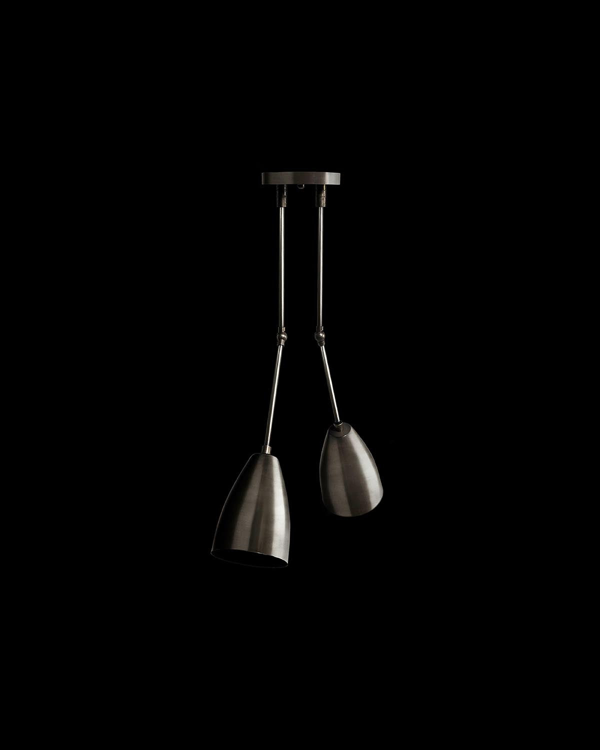 Minimalist black metal two-light downlight fixture with adjustable angled shades against a black background