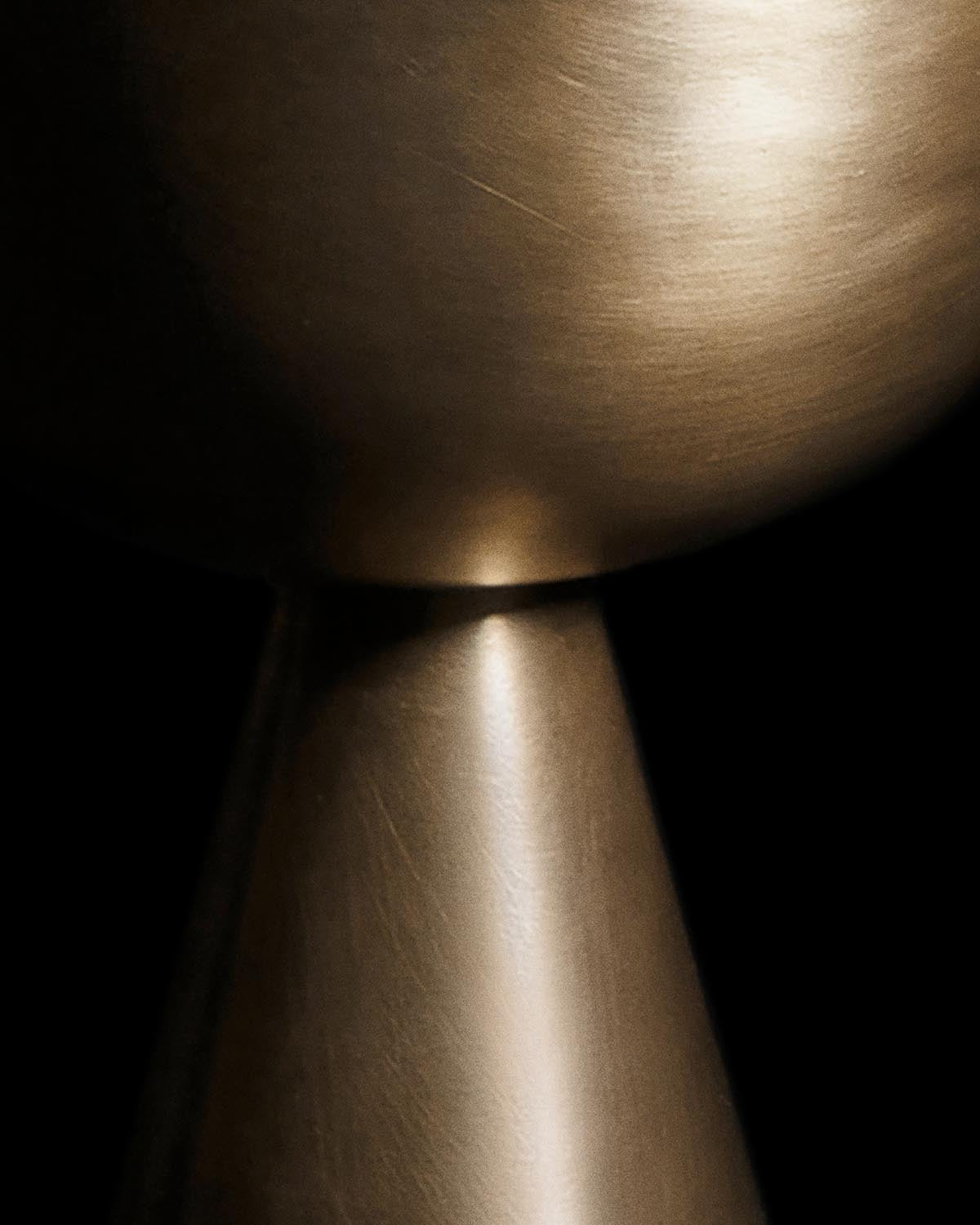 Close-up of a brushed metallic censer with smooth geometric curves against a black background